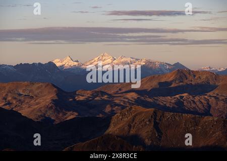 Matin d'automne dans les montagnes, pic enneigé lointain, premier plan éclairé par l'or Banque D'Images