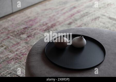Vases minimalistes sur un plateau noir dans un cadre serein et moderne Banque D'Images