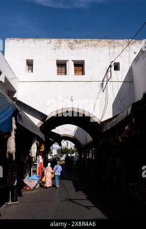 Une vue d'une arche dans le quartier Habous de Casablanca, Maroc, le 7 octobre 2023, avec des gens marchant et des étals de marché de chaque côté. Cette zone Banque D'Images