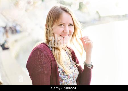 Jeune femme souriante avec de longs cheveux blonds, portant un dre floral Banque D'Images