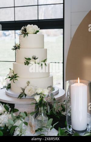 élégant gâteau de mariage à quatre niveaux avec fleurs blanches et verdure Banque D'Images