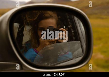 Femme voyageuse prend une photo dans le rétroviseur de la voiture. Banque D'Images
