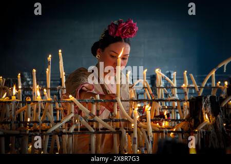 Jeune femme plaçant une bougie dans l'ermitage de la vierge pendant la célébration du pèlerinage d'El Rocio dans la ville d'Almonte, Huelva. Banque D'Images
