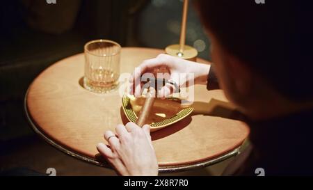 Homme coupant le cigare. Support. L'homme coupe la tête de cigare pour fumer. L'homme coupe le cigare professionnellement dans le restaurant Banque D'Images