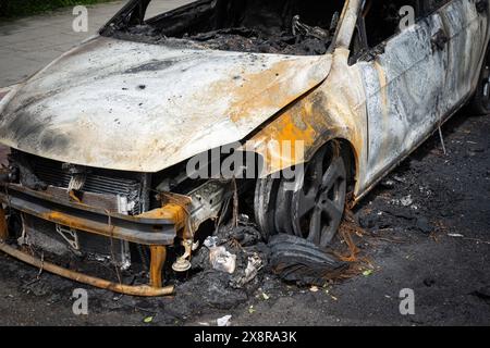 Une voiture brûlée avec intérieur et moteur détruits, vue sur le capot avec de lourdes traces de feu et côté gravement endommagé. Banque D'Images