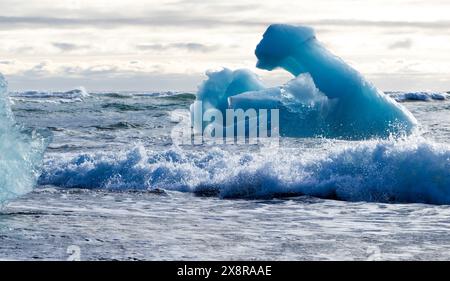 Un gros morceau de glace flotte dans l'océan. L'eau est agitée et le ciel est nuageux Banque D'Images