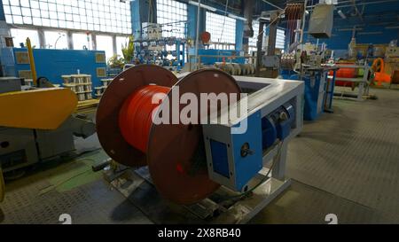 Bobine rotative avec fils en usine. Créatif. Enroulement du câble sur la bobine sur la machine de production. Procédé d'enroulement de câbles dans une installation métallurgique Banque D'Images