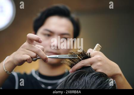 Coiffeur taillant la mèche de cheveux avec des ciseaux de coiffage Banque D'Images