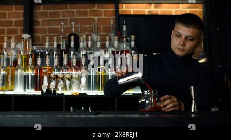 Le processus de préparation d'un cocktail alcoolisé au bar. Support. Jeune barman masculin au travail. Banque D'Images