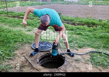 Pompage des eaux usées d'une fosse septique à l'aide d'une pompe submersible pour eaux usées. Banque D'Images