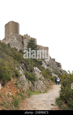 Deux personnes marchant jusqu'au chemin menant au Château Queribus, un ancien château en ruines dans le département de l'Aude, sud de la France Banque D'Images