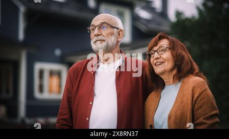 Heureux couple Senior posant à l'extérieur de leur zone résidentielle Home, embrassant les uns les autres. Adultes amoureux regardez la caméra et souriez, profitez de leur vie de retraite insouciante. Banque D'Images