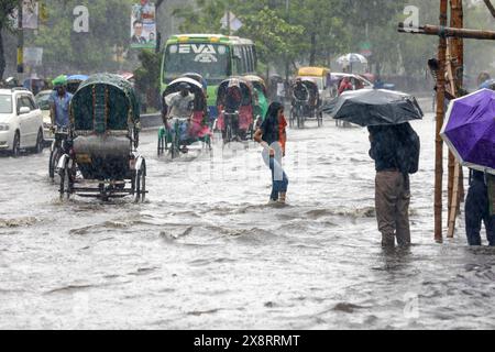 Les navetteurs souffrent des fortes pluies causées par le cyclone « Remal » à Dhaka, au Bangladesh. 27 mai 2024. Les gens de bureau et les personnes à faible revenu dans la capitale Dacca font face à des problèmes en raison des précipitations provoquées par le cyclone Remal qui ont commencé tôt le matin lundi. Les précipitations incessantes augmentent parfois alors qu'elles diminuent après un certain temps, ce qui entraîne une incertitude du mouvement des gens. Beaucoup de gens sortent de chez eux pour aller travailler, mais les transports en commun sont insuffisants. Photo de Suvra Kanti Das/ABACAPRESS. COM Credit : Abaca Press/Alamy Live News Banque D'Images