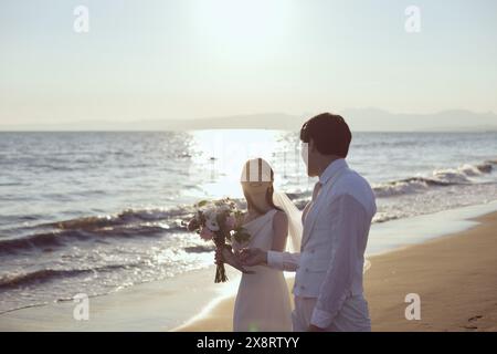 Couple japonais nouvellement marié debout sur la plage Banque D'Images