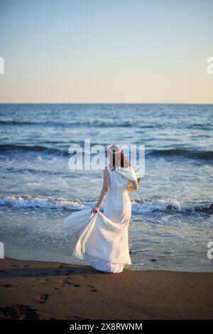 Mariée japonaise marchant sur la plage au coucher du soleil Banque D'Images