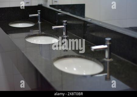 Lavabos dans la salle de bain publique avec robinets à la mise au point sélective Banque D'Images