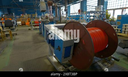 Bobine rotative avec fils en usine. Créatif. Enroulement du câble sur la bobine sur la machine de production. Procédé d'enroulement de câbles dans une installation métallurgique Banque D'Images