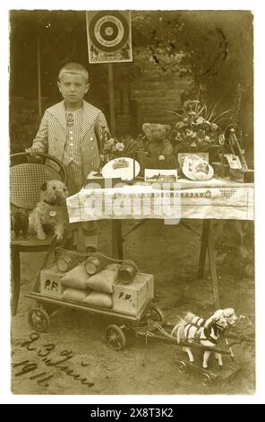 Original début des années 1900 carte postale de jeune garçon, portant un costume de marin intelligent, exposant ses jouets à l'extérieur dans son jardin, anniversaire présente peut-être. Les jouets comprennent Teddy, chien de jouet mou, chariot à cheval, garçon est Paul F peut-être. Daté du 23 juin 1911 sur le recto de la carte postale. Posté à Londres depuis l'Allemagne. Garçons victoriens / garçons édouardiens. Enfant victorien. Banque D'Images