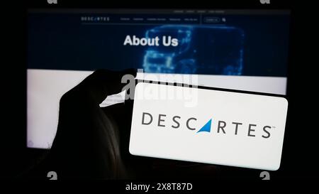 Personne tenant un téléphone intelligent avec le logo de la société canadienne Descartes Systems Group Inc devant le site Web. Concentrez-vous sur l'affichage du téléphone. Banque D'Images