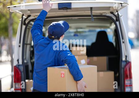 Livreur japonais vérifiant les cases dans la voiture Banque D'Images