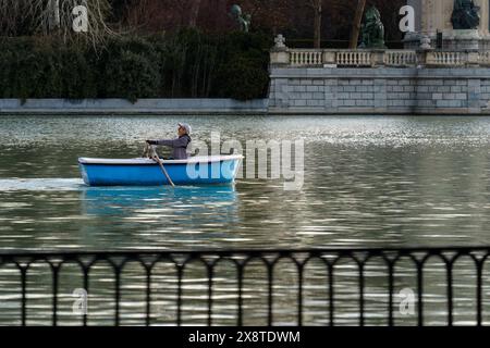 Madrid, Espagne. 12 février 2024 - homme ramant un bateau bleu sur le grand étang du parc El Retiro Banque D'Images