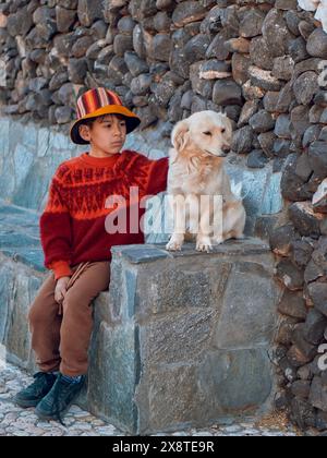 garçon latino assis sur un banc de ciment avec son chien. concept d'amitié comme enfant unique. Banque D'Images