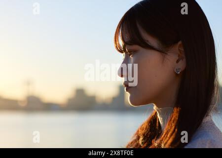 Femme japonaise regardant au-dessus de l'eau au coucher du soleil Banque D'Images