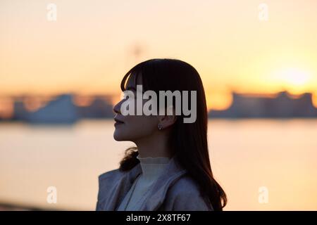 Femme japonaise regardant au-dessus de l'eau au coucher du soleil Banque D'Images