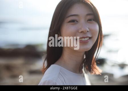 Femme japonaise aux cheveux longs souriant à la caméra Banque D'Images