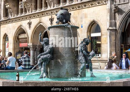 Fontaine de poissons et en arrière-plan la façade néo-gothique du nouvel hôtel de ville dans un style néo-gothique sur Marienplatz, centre-ville, Munich, Haut Banque D'Images