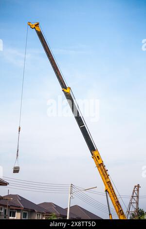 bras télescopiques jaunes de camion de grue de construction mobile soulevant la dalle de béton à la maison de construction au chantier de construction Banque D'Images