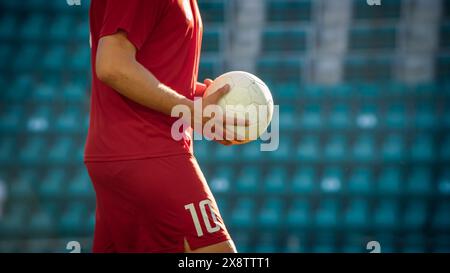 Concentrez-vous sur les mains d'un joueur de football professionnel marchant sur le terrain du stade Green Grass et tenant Un ballon. Joueurs se reposant entre attaque et Défense pendant le championnat de football. Prise de vue à angle bas. Banque D'Images
