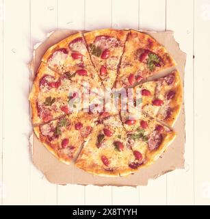 délicieuse pizza cuite isolée sur la vue de dessus de table en bois blanc, tonifiée avec filtre instagram Banque D'Images