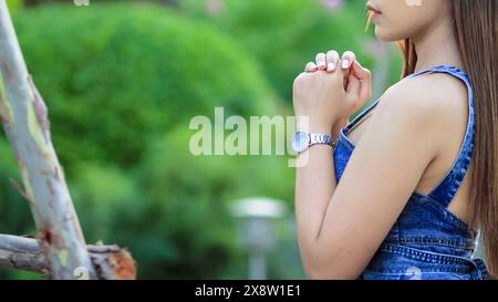 La jeune femme a serré ses mains ensemble dans la prière demandant pardon de Dieu sur la base de ses croyances chrétiennes et de sa foi dans les enseignements de Dieu. concept pr Banque D'Images