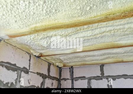 Isolation du plafond dans la maison avec de la mousse de polyuréthane. Mousse isolante entre poutres en bois Banque D'Images