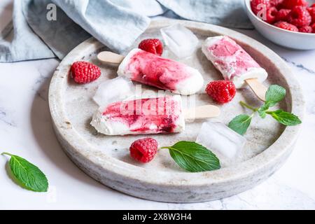 Rafraîchissant popsicles à la framboise maison sur plateau avec de la glace et des baies Banque D'Images