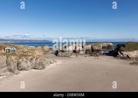 paysage côtier avec plage de sable, formations rocheuses, ciel dégagé et plan d'eau lointain Banque D'Images