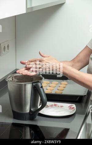 saupoudrer la farine sur un mélangeur de cuisine avec de la pâte à biscuits, indiquant la préparation de cuisson sur une cuisinière moderne Banque D'Images