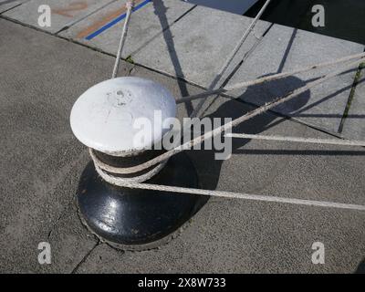 Borne d'amarrage avec lignes d'amarrage sur un quai de navire en béton Banque D'Images