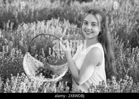 fille positive dans le champ de fleurs de lavande. adolescente tenant un bouquet de fleurs de lavande. Portrait d'une belle jeune fille aux cheveux longs dans un Banque D'Images