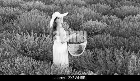 adolescente positive avec de la lavande tenant un bouquet de fleurs dans une robe marchant dans le parc de lavande Banque D'Images