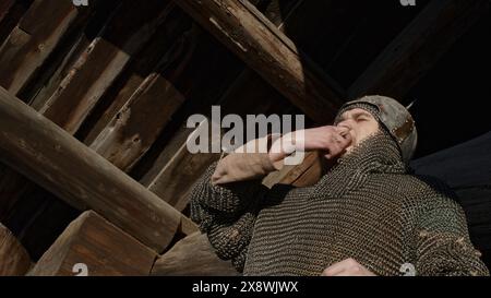 Gros plan d'un guerrier en armure de mailles sifflant avec ses doigts. Support. Ancien guerrier nea maison en bois. Banque D'Images