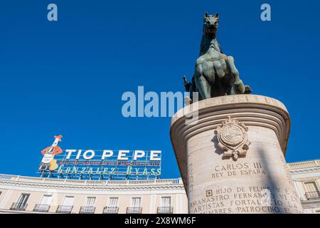 Madrid, Espagne. 2024 : Puerta del sol, célèbre place de Madrid. Statue équestre du roi Carlos III et la publicité emblématique du vin. Banque D'Images