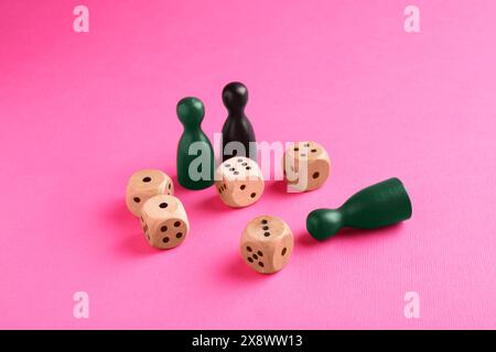 Dés en bois et pièces de jeu de couleur sur fond rose Banque D'Images