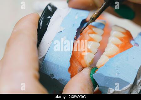 Un technicien dentaire utilise des outils spécialisés pour fabriquer et former méticuleusement des prothèses dentaires, assurant un ajustement parfait pour les patients dentaires. Banque D'Images