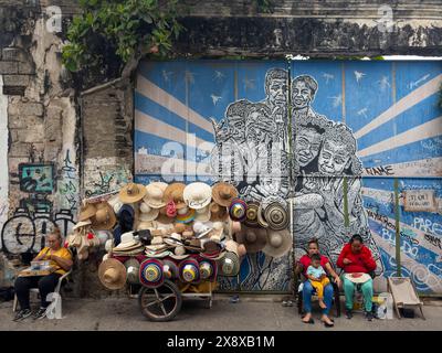 Vendeurs de chapeaux avec des peintures murales dans le quartier Getsemani de Carthagène illustrant la culture afro-colombienne des Caraïbes trouvée dans cet héritage mondial de l'UNESCO Banque D'Images