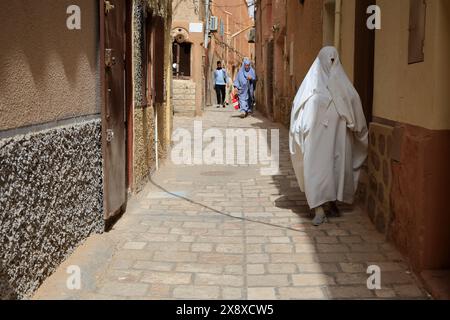 Femme mozabite en haik blanc marchant dans la rue de Ksar Ghardaia. Ghardaia Province.northern Sahara. Algérie Banque D'Images