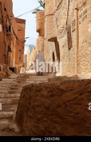 Femme mozabite voilée en haik blanc dans la rue de Beni Isguen. Beni Isguen est l'un des 5 Ksars (colonie fortifiée) de la vallée du Mzab. Province de Ghardaia. Sahara du Nord. Algérie Banque D'Images