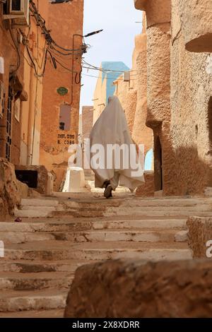 Femme mozabite voilée en haik blanc dans la rue de Beni Isguen. Beni Isguen est l'un des 5 Ksars (colonie fortifiée) de la vallée du Mzab. Province de Ghardaia. Sahara du Nord. Algérie Banque D'Images