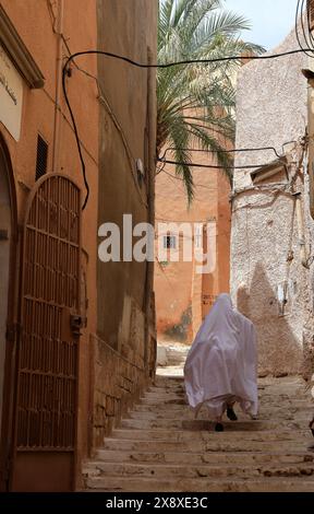 Femme mozabite voilée en haik blanc dans la rue de Beni Isguen. Beni Isguen est l'un des 5 Ksars (colonie fortifiée) de la vallée du Mzab. Province de Ghardaia. Sahara du Nord. Algérie Banque D'Images